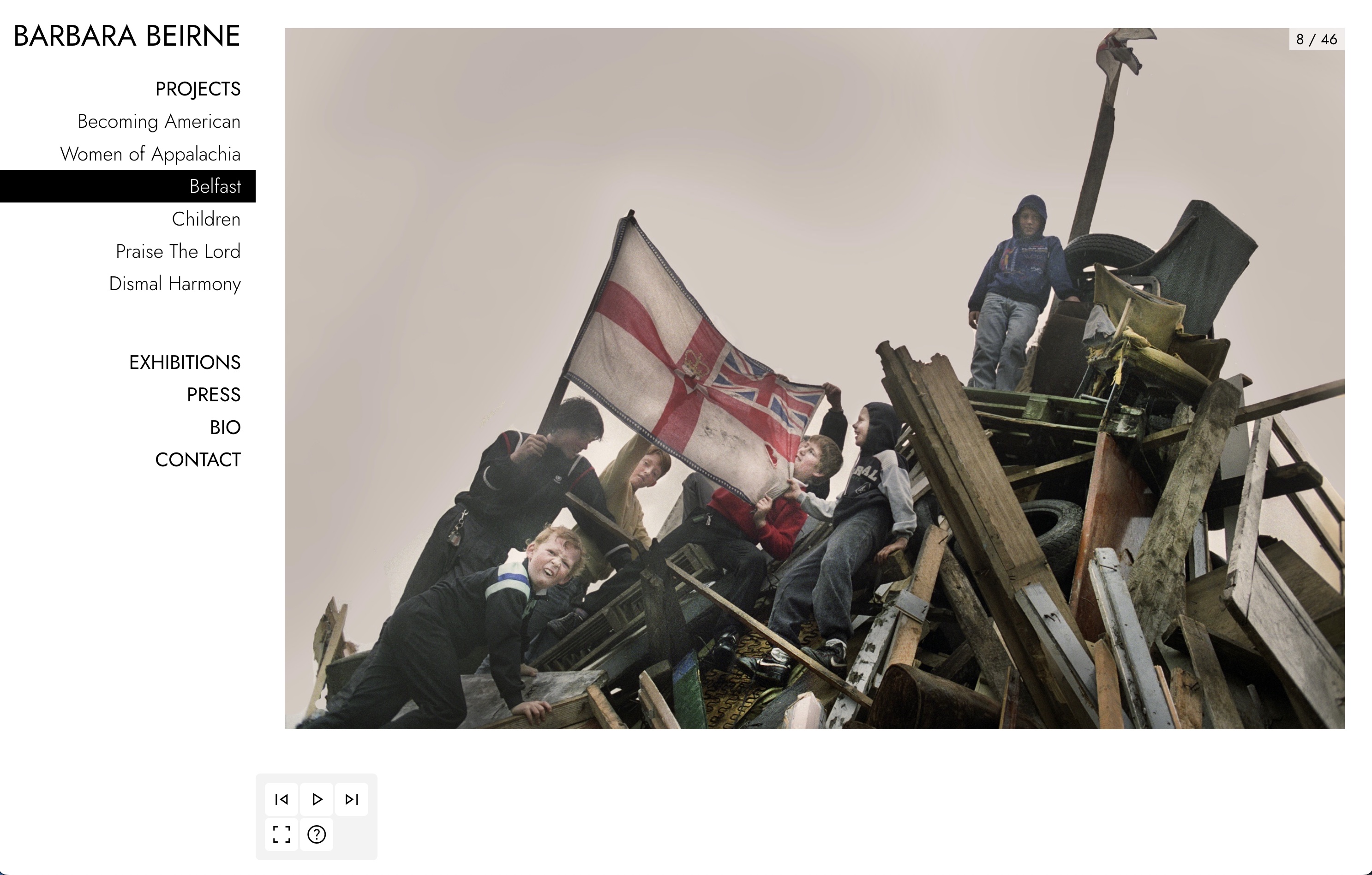A group of children climbing on a large pile of debris, one waving the Ulster Banner. Image by Barbara Beirne